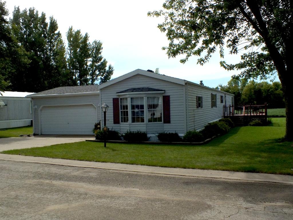 Blue manufactured home with mature trees at Knollwood Estates