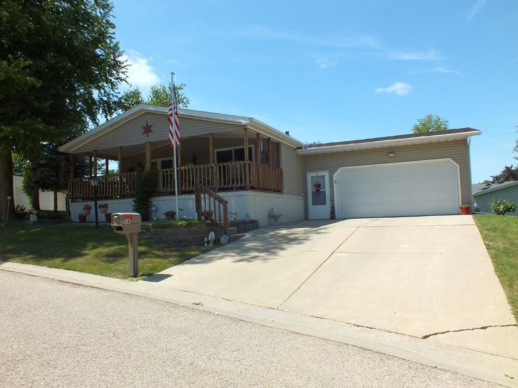 Home with covered porch, American flag, and two-car garage at Knollwood Estates